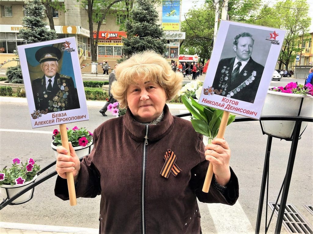 Tamara standing with the photos of her lost loved ones