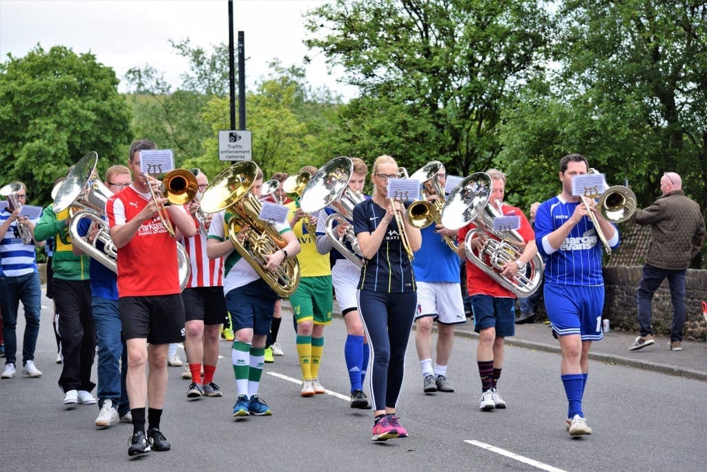 Kitted out in footbal shirts, the March of the Day Band play theThe Match of the Day theme tune as they parade through Denshaw