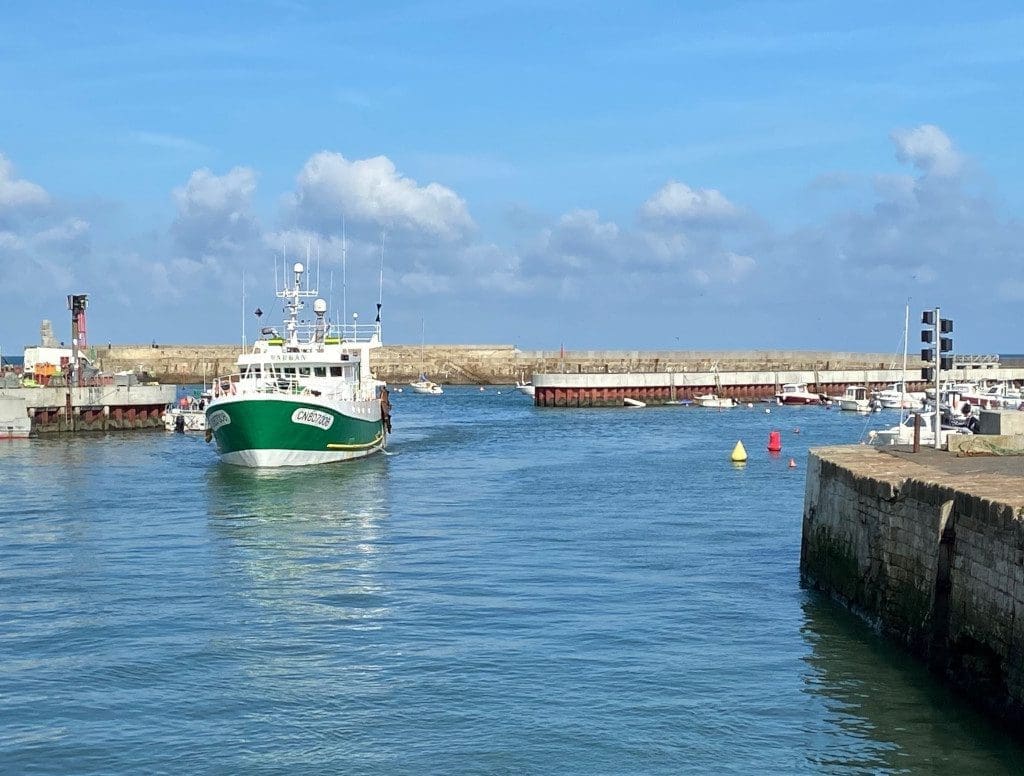 camping in Brittany A boat sailing into the harbour at Port-en-Bessin