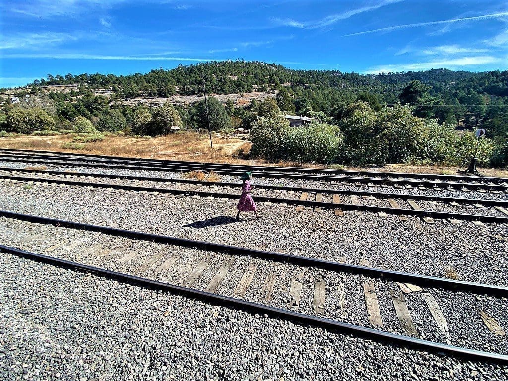 A girl walking along the tracks next to Chepe Express