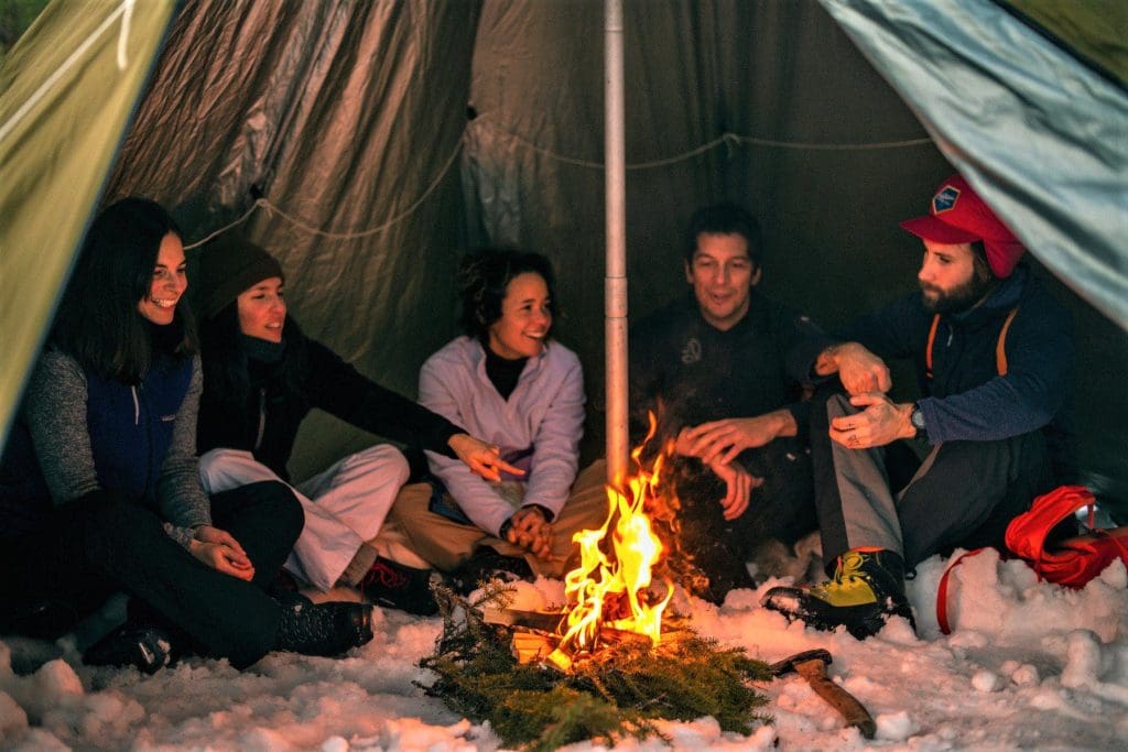 A group of friends having cosy fun in a tipi tent in the middle of winter in Sweden. Copyright Slow Adventure Ltd