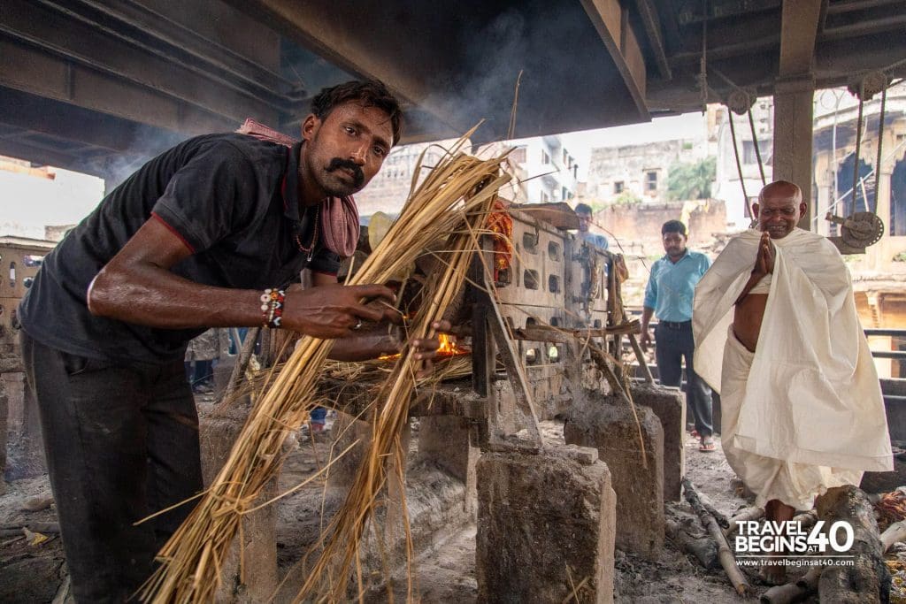 Workers assist to ensure the pyre is properly lit