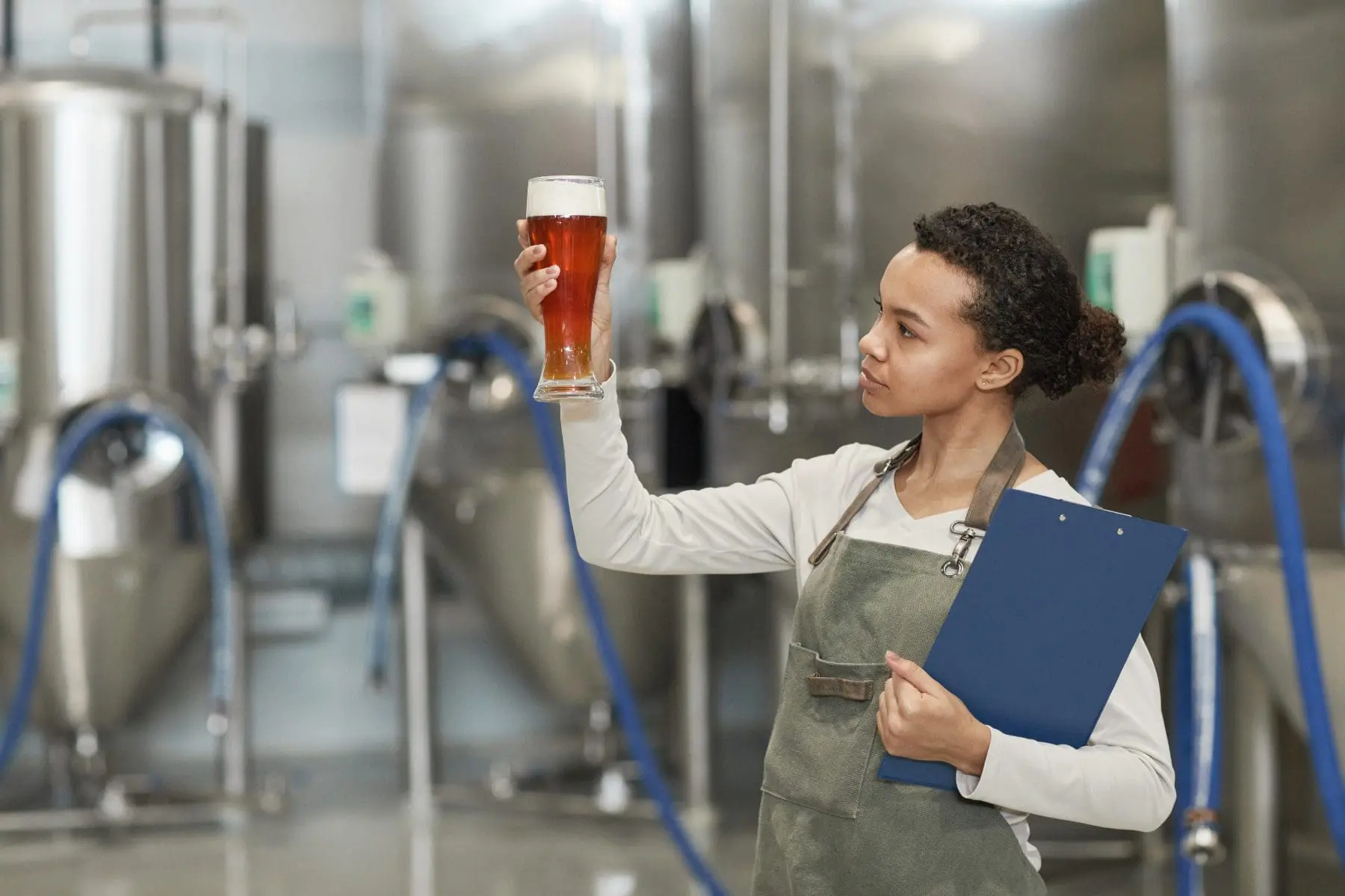 Young Woman Looking at Beer Glass at Brewery