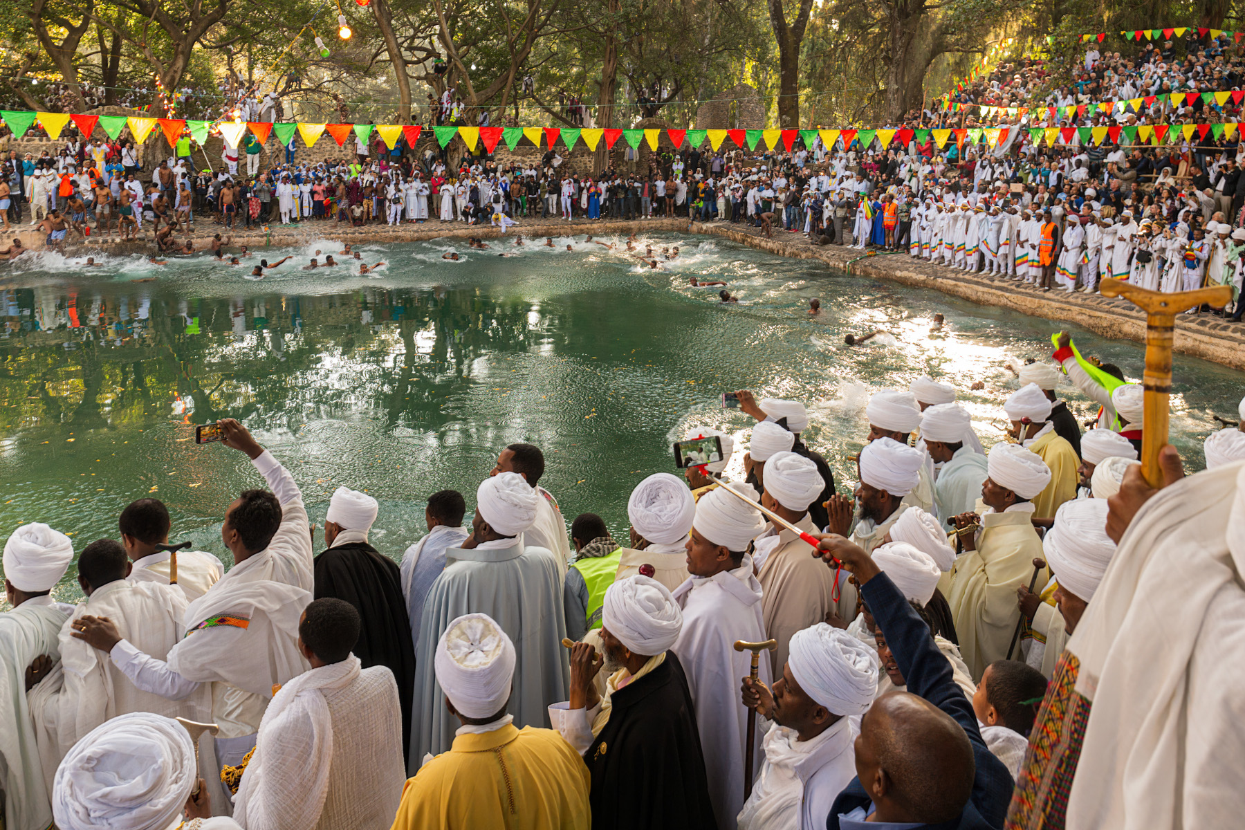 GONDAR, ETHIOPIA – JAN 19, 2019: Young men jumping into the holy water at Timkat festival at Fasilides Bath. Timkat festival