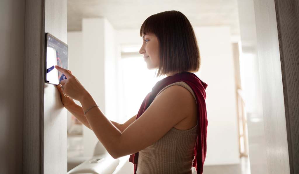 Woman adjusting smart home thermostat on the wall