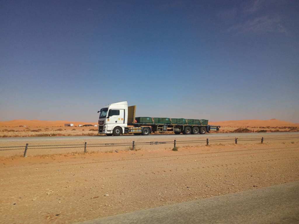 White semi-truck transporting cargo on a desert highway